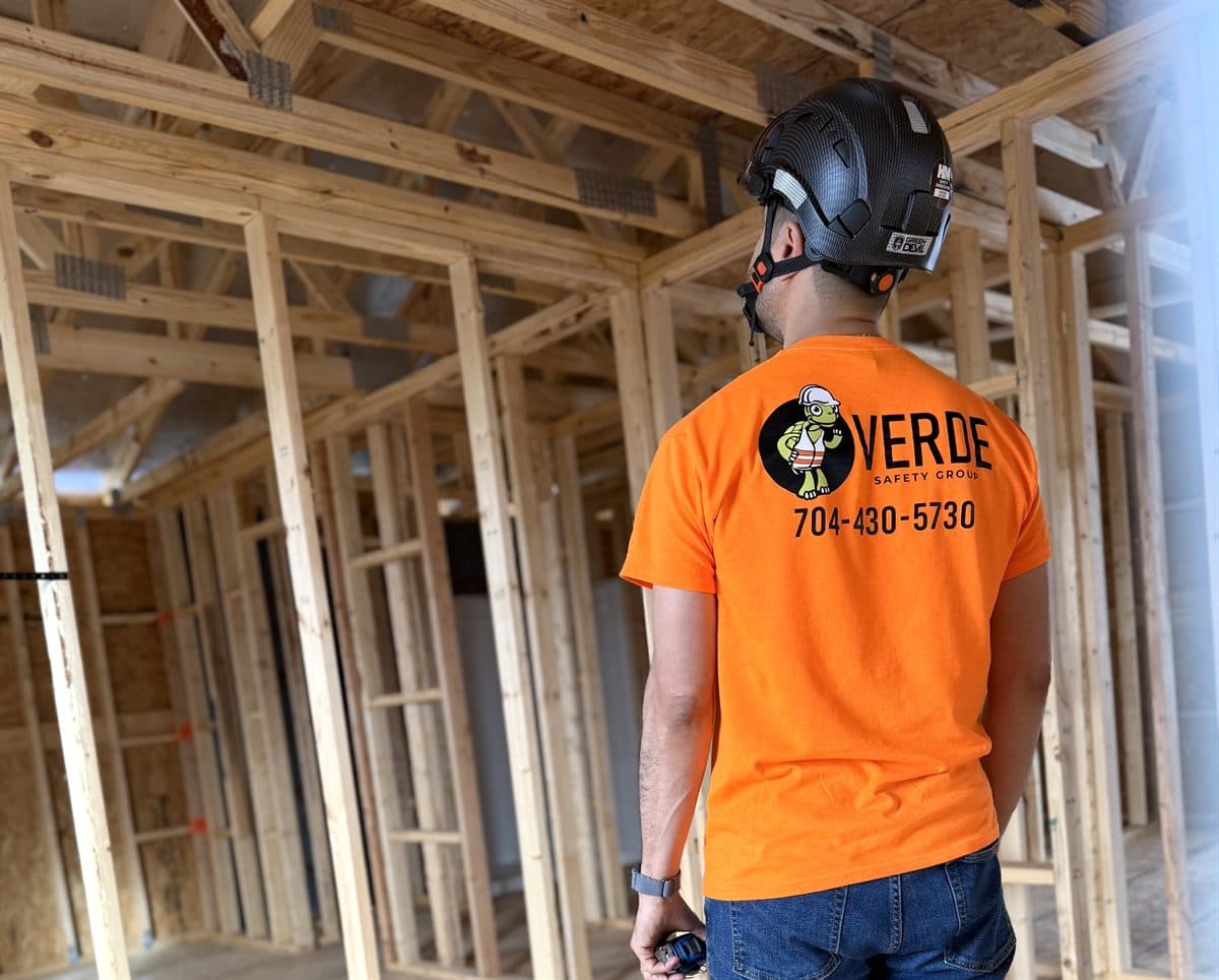 A worker in a hard hat walking through a wood-framed building