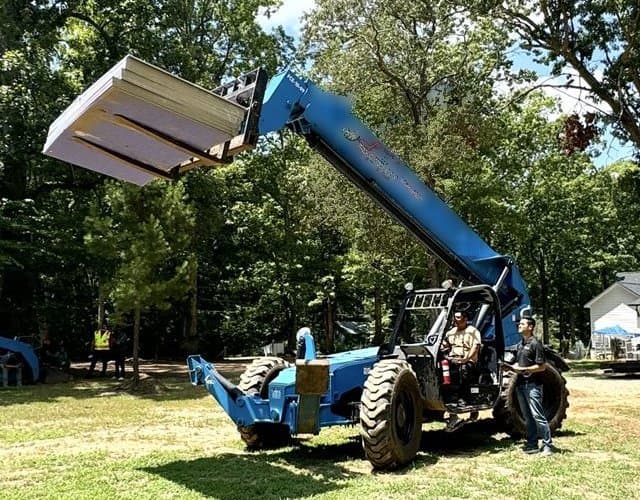 Edwin Cueva evaluating a telehandler operator with the boom raised and a load of lumber overhead