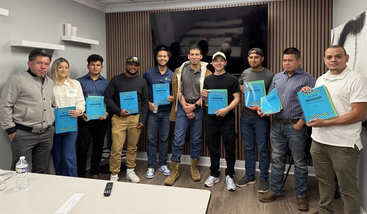 An OSHA 10 class holding their Spanish-language construction workbooks with Edwin Cueva